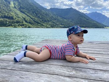 Cute baby boy lying on floor against sea