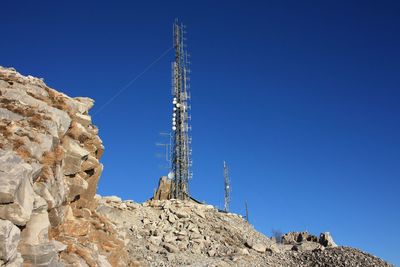 Low angle view of communications tower against clear blue sky