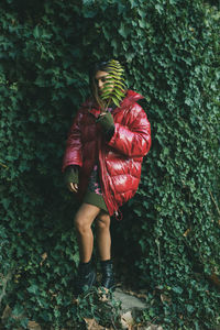 Full length of woman standing against red plants