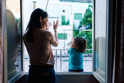 Rear view of women standing in glass window