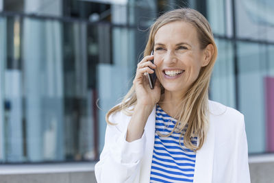 Smiling blond businesswoman using smartphone