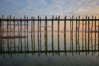 Wooden posts on beach against sky during sunset