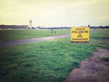 Information sign on field against sky