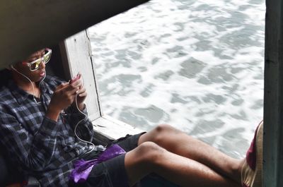 Close-up of hand holding mobile phone while sitting outdoors