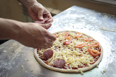 Food cooking, culinary and people concept - cook or baker hand with pizza on peel at pizzeria