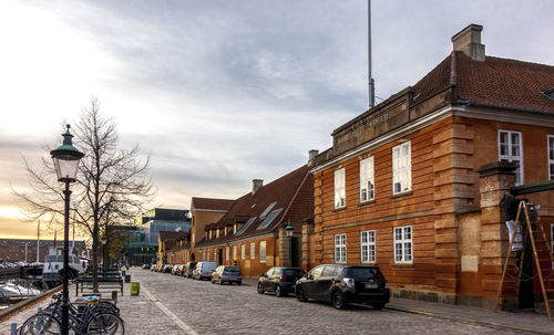 Cars on street by buildings against sky in city