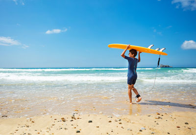 Rear view of woman standing at beach against sky