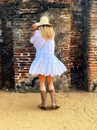 Full length of woman standing against brick wall