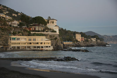 Buildings by sea against clear sky