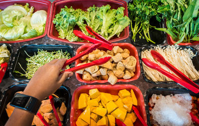 High angle view of person holding serving tongs at market