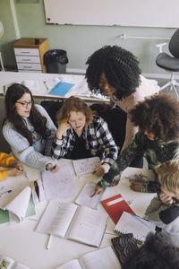 High angle view of teacher teaching diverse students in classroom