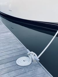 High angle view of rope tied on dock against water and vessel