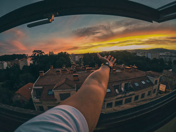 Midsection of man against buildings in city during sunset