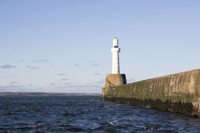 Lighthouse by sea against sky