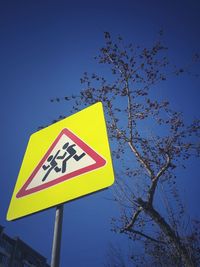 Low angle view of road sign against clear blue sky