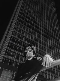 Portrait of young man standing against built structure at night