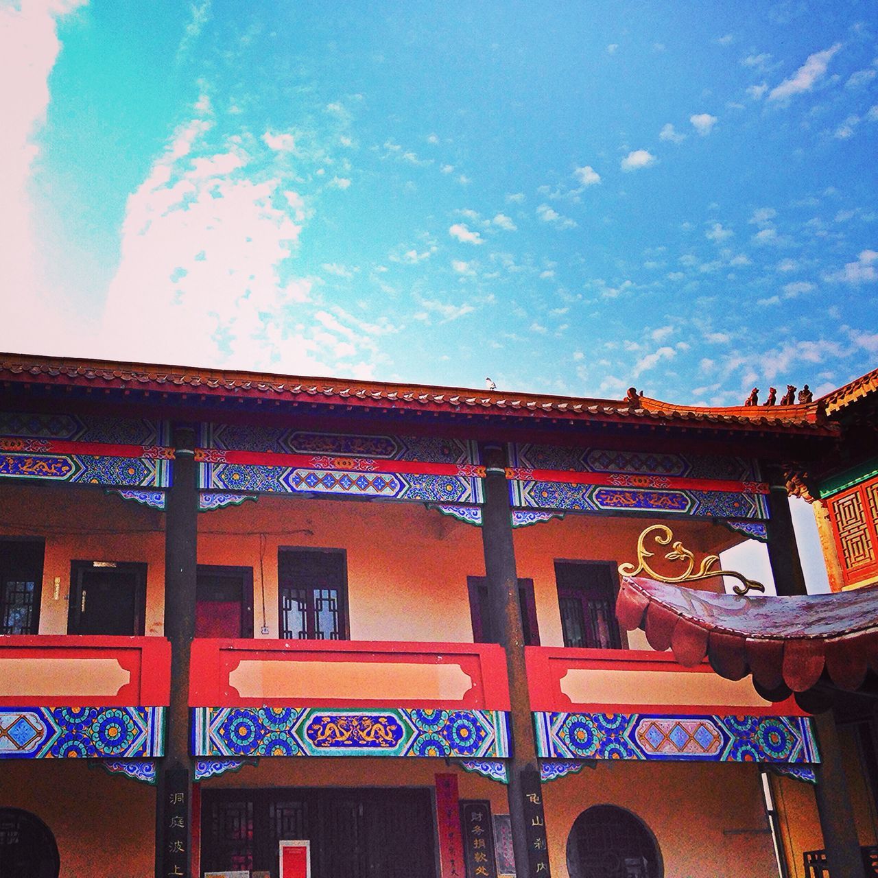 architecture, built structure, low angle view, building exterior, sky, art and craft, arch, outdoors, blue, cloud - sky, day, red, no people, art, roof, window, creativity, cloud, ornate, building