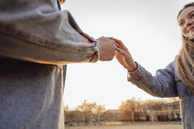 Hands of man and woman on sky background