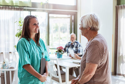 Young nurse talking with senior woman at nursing home