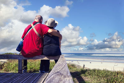 Rear view of man standing at beach against sky