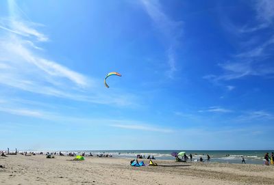 Scenic view of people on beach against sky