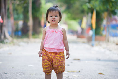 Portrait of cute baby girl standing on footpath