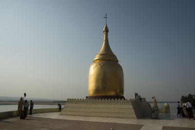 People at gold shrine against clear sky