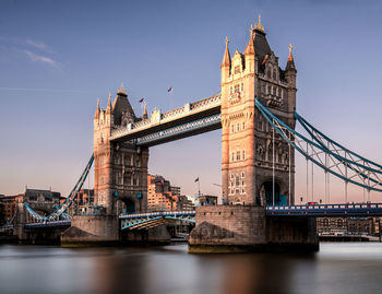 Tower bridge over river against during sunset