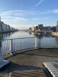 Bridge over river by buildings in city against sky