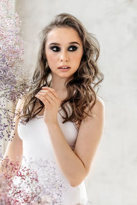 Portrait of young woman standing against wall