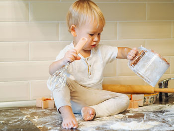 Cute toddler playing with flour at kitchen