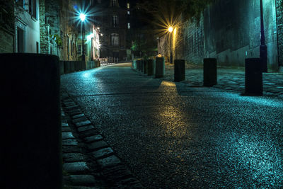 Empty road by houses on street at night