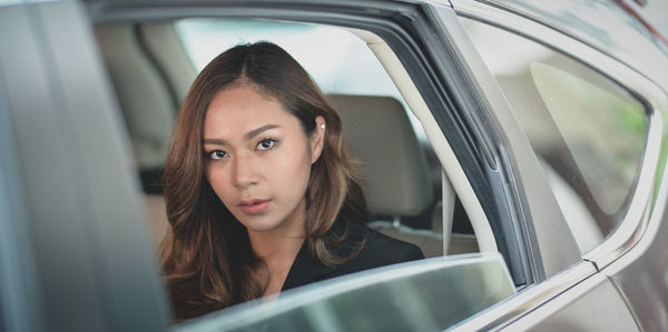 Portrait of woman sitting in car seen through window