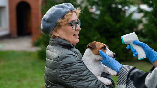 Woman holding dog with mobile phone