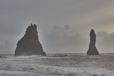 Rock formation on beach against sky
