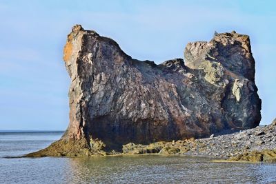 Rock formation on beach against sky
