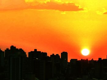 Silhouette buildings against orange sky