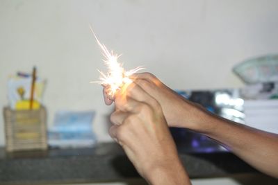 Midsection of woman holding sparkler at night