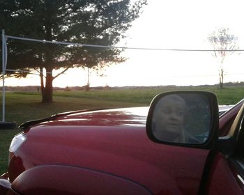 Close-up of side-view mirror against car on road