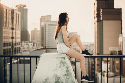 Full length of young woman against railing in city