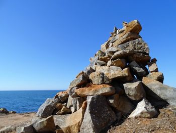 Rocks in sea against clear blue sky