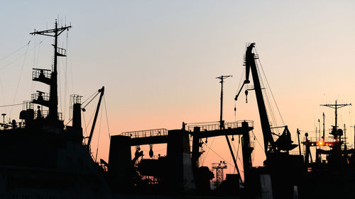 Silhouettes of ships and container cranes in sea port, sunset background. industrial landscape