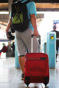 Low section of man with luggage standing at railroad station platform