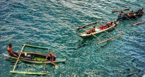 High angle view of men sitting on fishing boats in sea