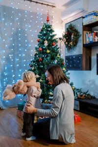 Side view of woman with teddy bear at home