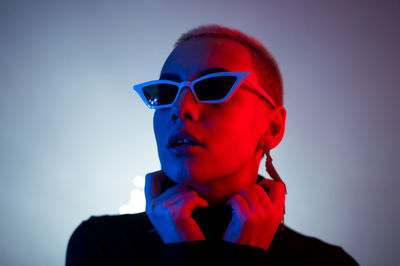 Portrait of young man wearing sunglasses against gray background