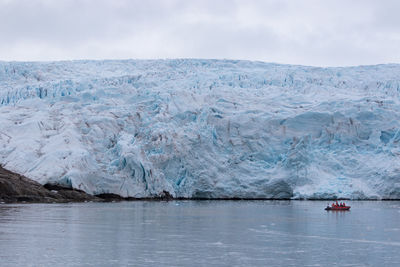 Unidentified tourists on a speedboat admiring large glacier from a close distance in svalbard