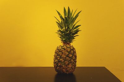 Close-up of fruit on table against yellow wall