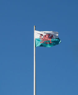 Low angle view of flags against clear blue sky