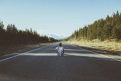 Rear view of man on road against clear sky